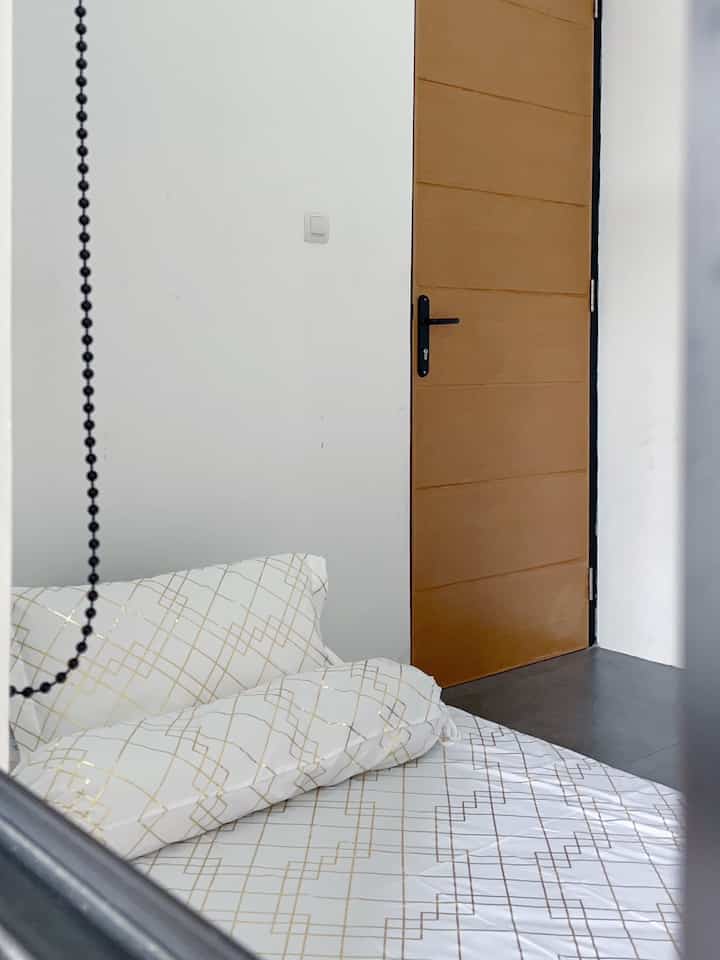 Small bedroom in white and brown tones featuring a single bed and simple layout for a spacious feel