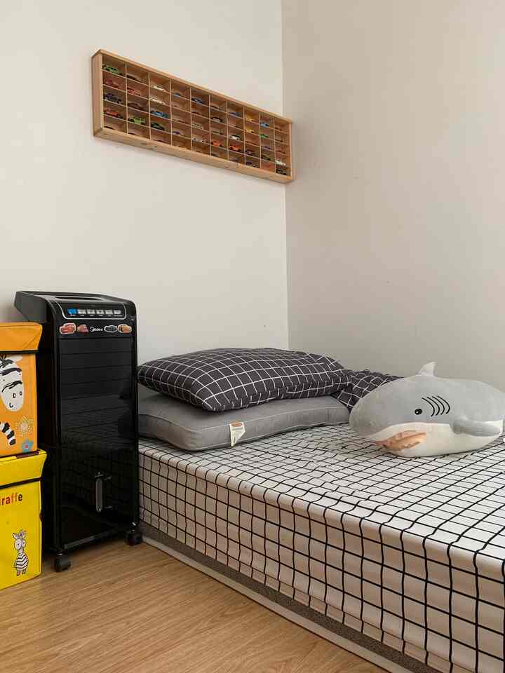 Bright white walls and wood-tone floor in a 6-tatami sized room featuring a black air cooler, kids' bed with plush toy, and colorful storage boxes creating a cozy atmosphere