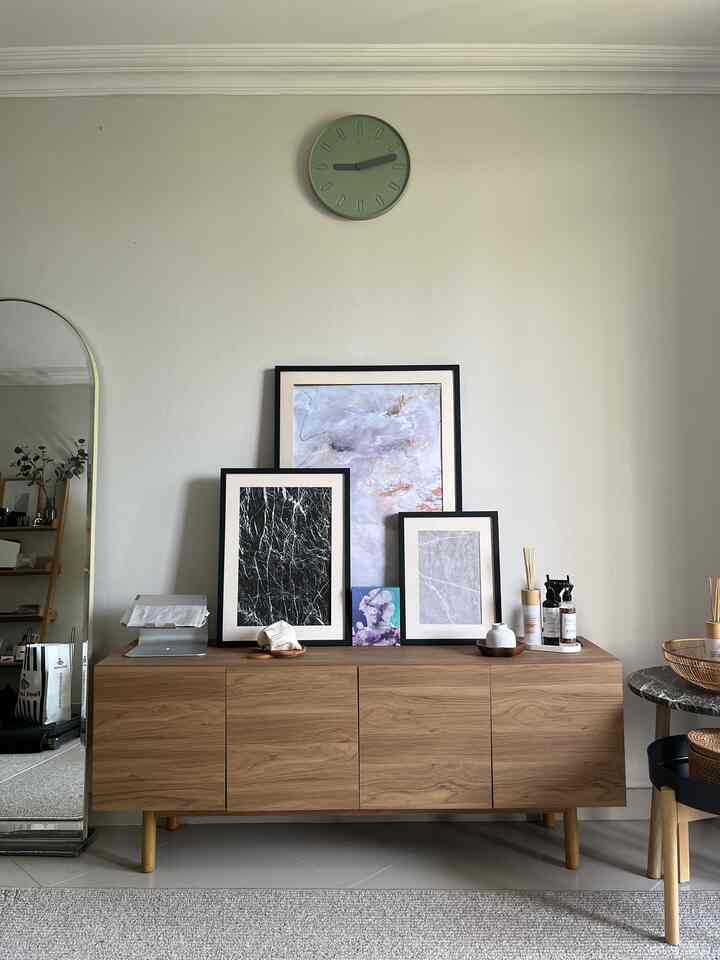 Natural-colored living room with wood tone sideboard featuring picture frames and a standing mirror in a neat, calm setting