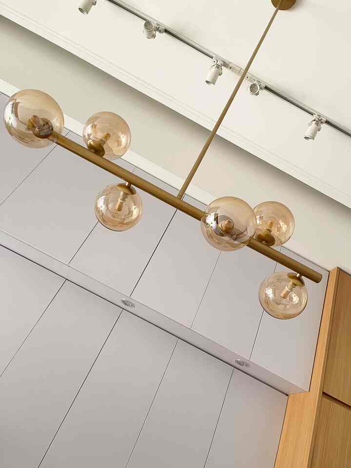 Modern kitchen space with white and wood tones featuring a gold pendant light, showcasing a clean aesthetic