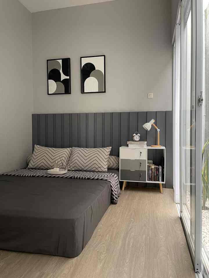 Gray and natural tone bedroom featuring a large bed, nightstand, and table lamp with a simple modern atmosphere