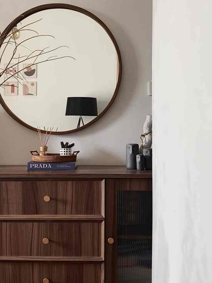 Vintage style entrance space featuring dark brown wooden cabinet and large round mirror with natural décor
