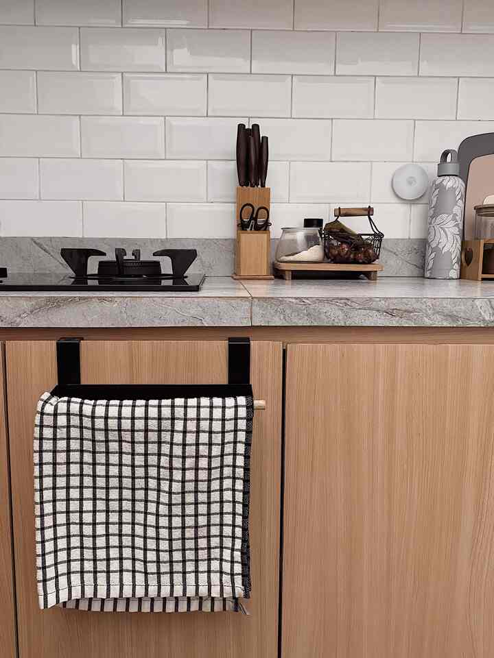 Natural color and wood tone kitchen featuring gray marble countertop and white tiled backsplash with a clean atmosphere