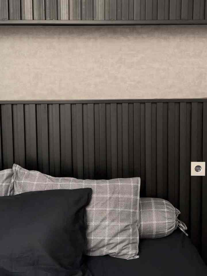 Black and gray toned bedroom featuring checkered pillows and solid bedding in a modern setting