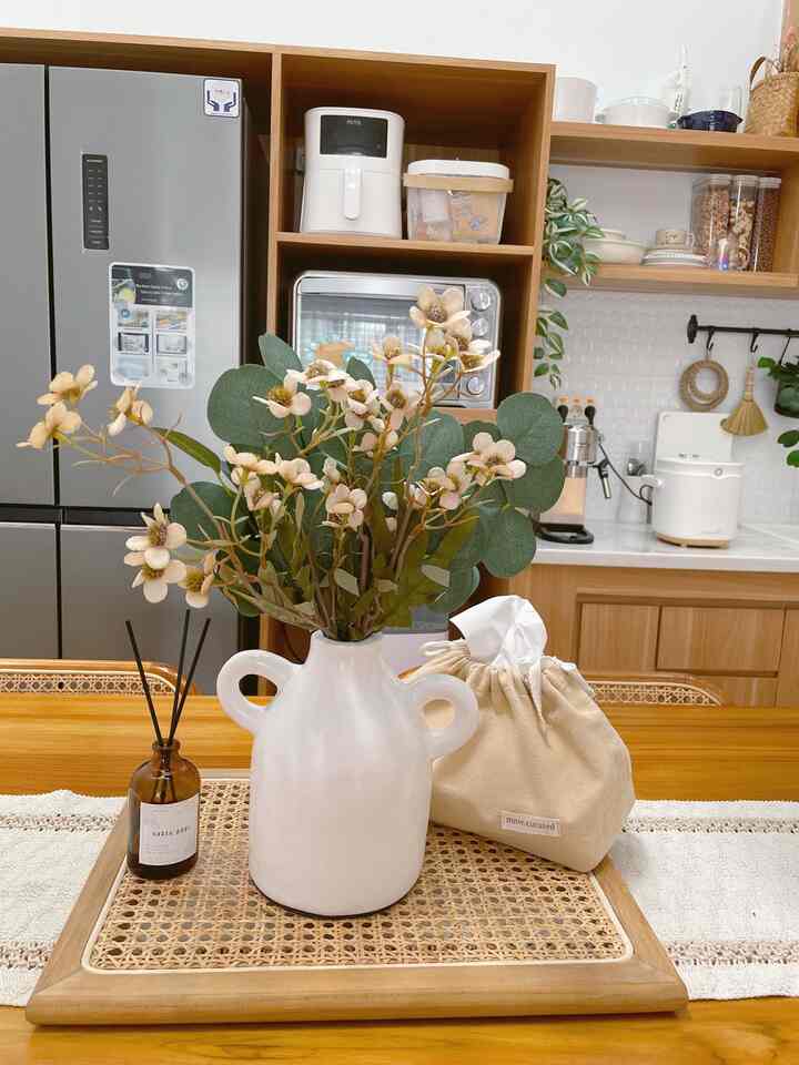 Natural wood tone and white themed dining room featuring a dining table with a ceramic vase centerpiece creating cozy atmosphere
