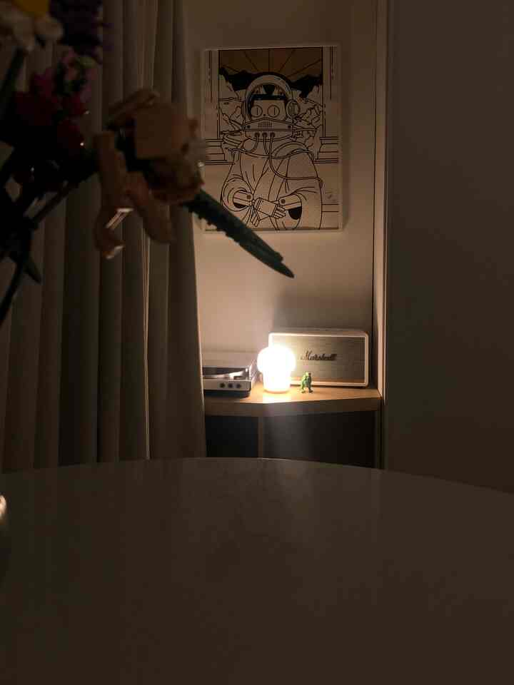 Cozy studio apartment balcony corner in warm beige and white tones featuring a turntable and speaker with soft lighting