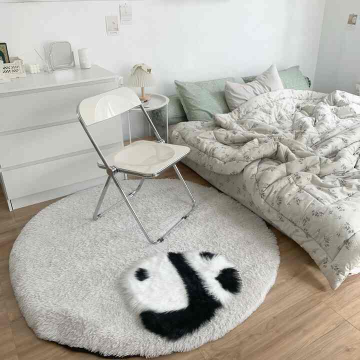 White and natural color toned bedroom featuring a round panda-shaped carpet and simple furniture, creating a cozy atmosphere
