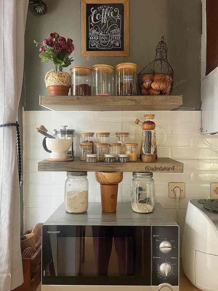 Kitchen corner with brown wood tone and white tiles featuring a microwave and neatly arranged kitchen utensils