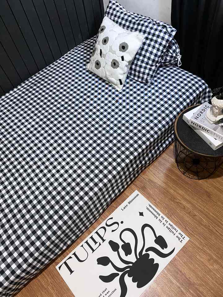 Monotone wood-toned bedroom featuring black and white gingham bedding and a wire-frame side table with storage, showcasing a modern vibe