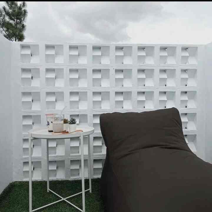White-toned small rooftop area featuring a brown bean bag and a white side table with a cozy atmosphere