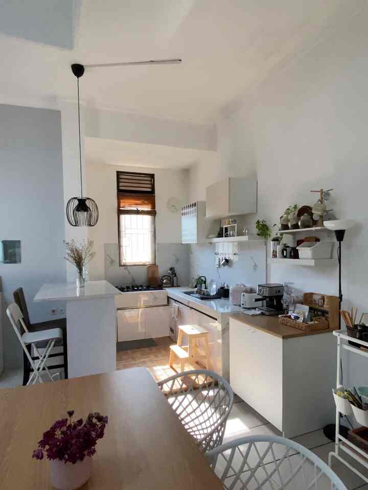 White and wood tone kitchen and dining room with natural lighting and a clean layout in a long and narrow space