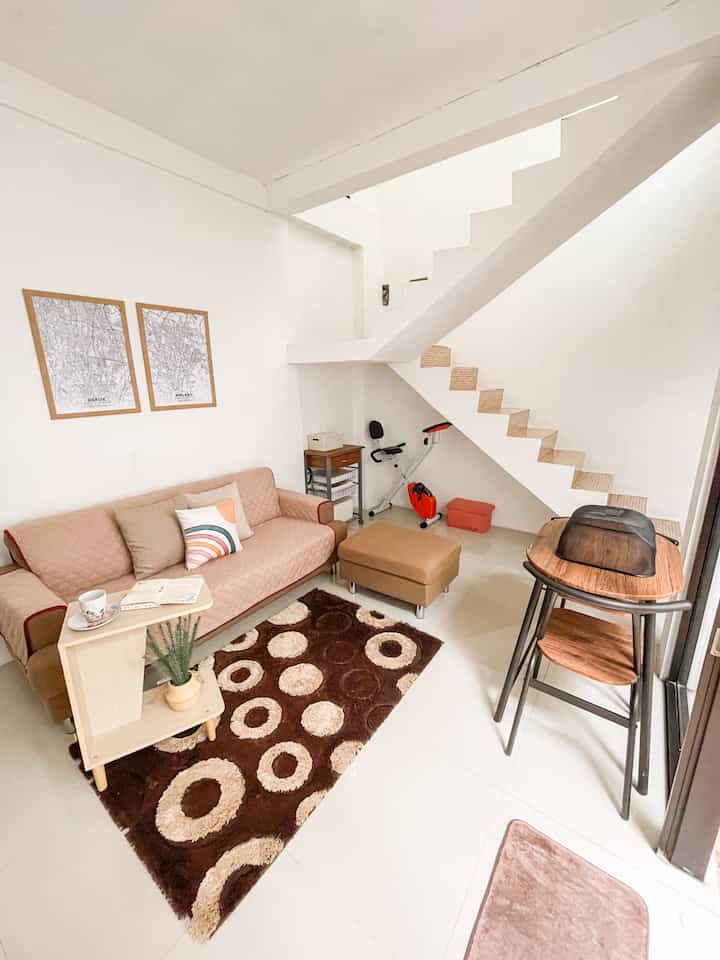 Brown and white toned living room featuring sofa, rug, and exercise bike with a natural and cozy atmosphere