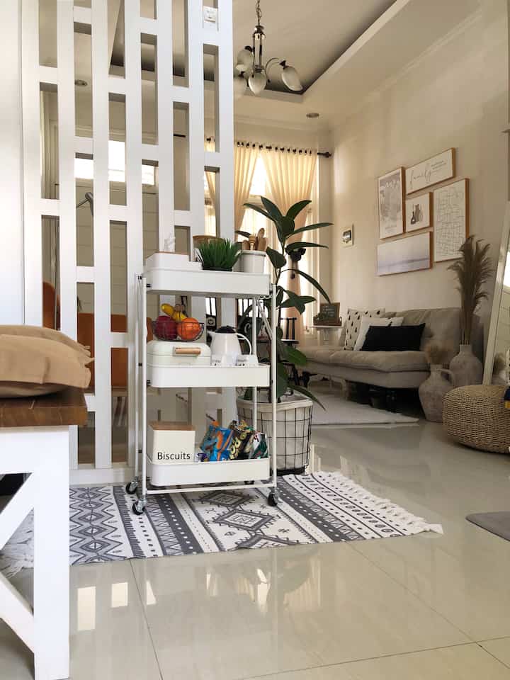 Bright kitchen and living room with white and natural tones, featuring a 3-tier bar cart and a bohemian style carpet, creating a cozy atmosphere