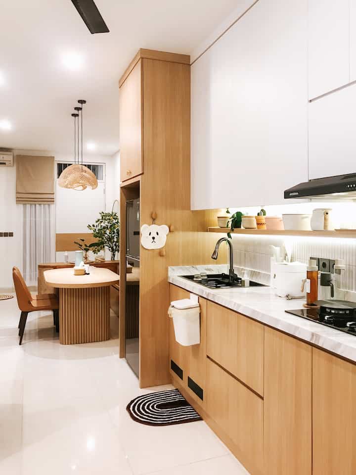 Bright white and warm wood-tone kitchen and dining room featuring utensils and pendant lighting in a cozy open space