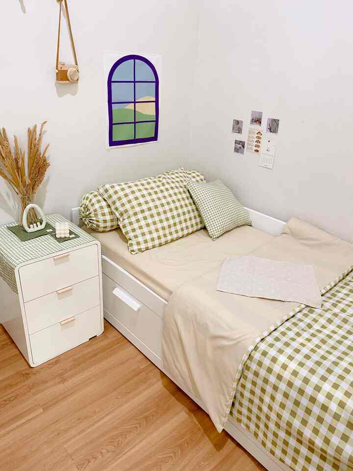 Minimal bedroom with white and beige tones featuring checkered pillows and bedding in a small cozy space
