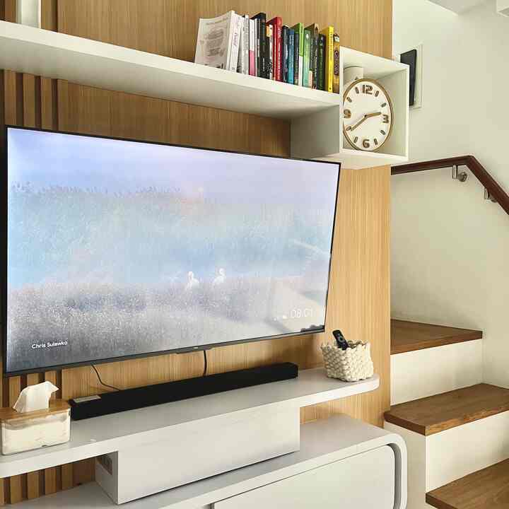 Modern and minimal living room featuring white and wood tone elements with large TV and soundbar setup