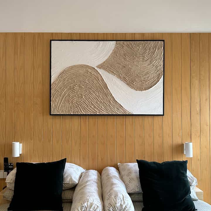 Natural wood tone wall with white bedding in a Japandi style bedroom interior