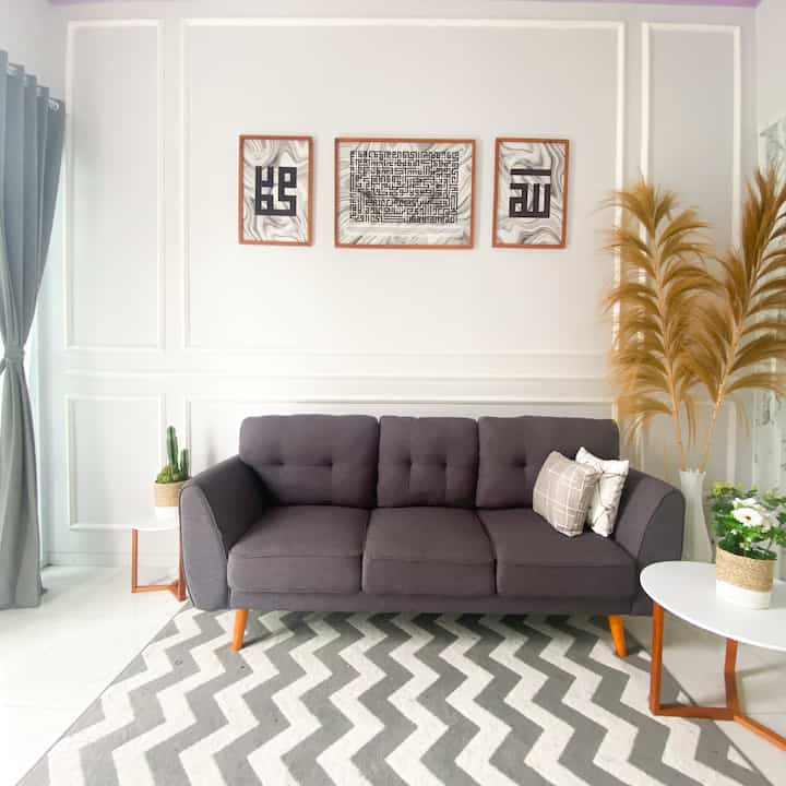 White and gray toned living room featuring a central gray sofa and zigzag patterned carpet in a simple interior space