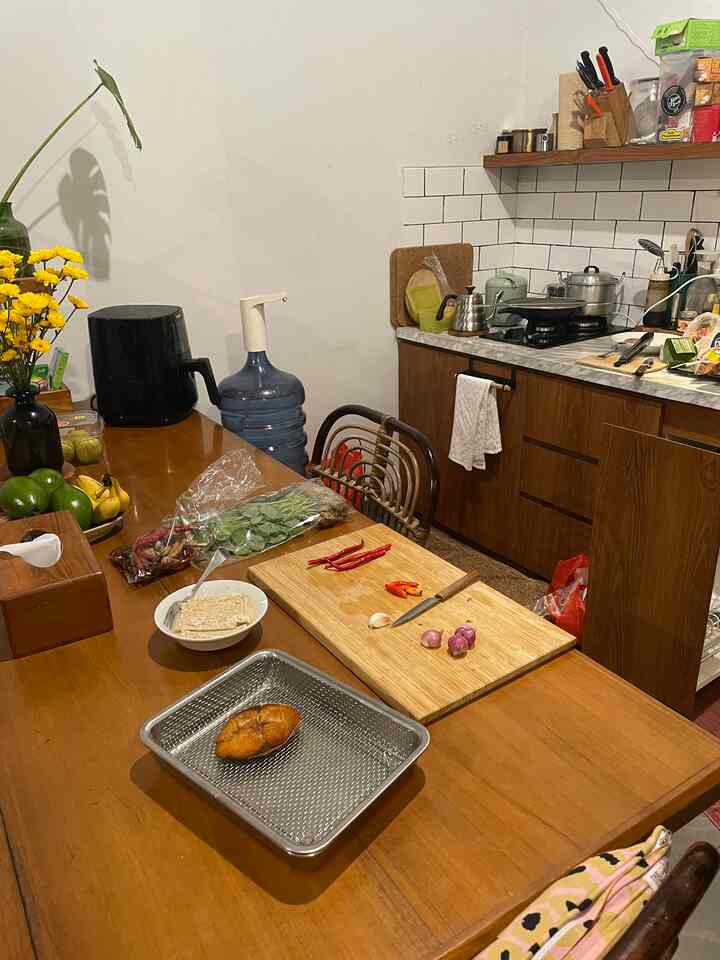 Natural tone small kitchen space featuring a large wooden dining table and cooking utensils with a cozy atmosphere