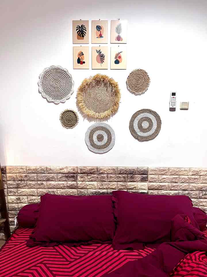 Red-toned bedroom with beige patterned placemats and art pieces decorating the wall, creating a simple space