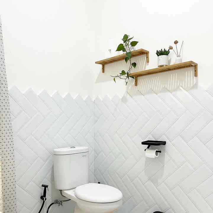 White-toned bathroom space featuring wooden wall shelves with plants, creating a clean minimalist look