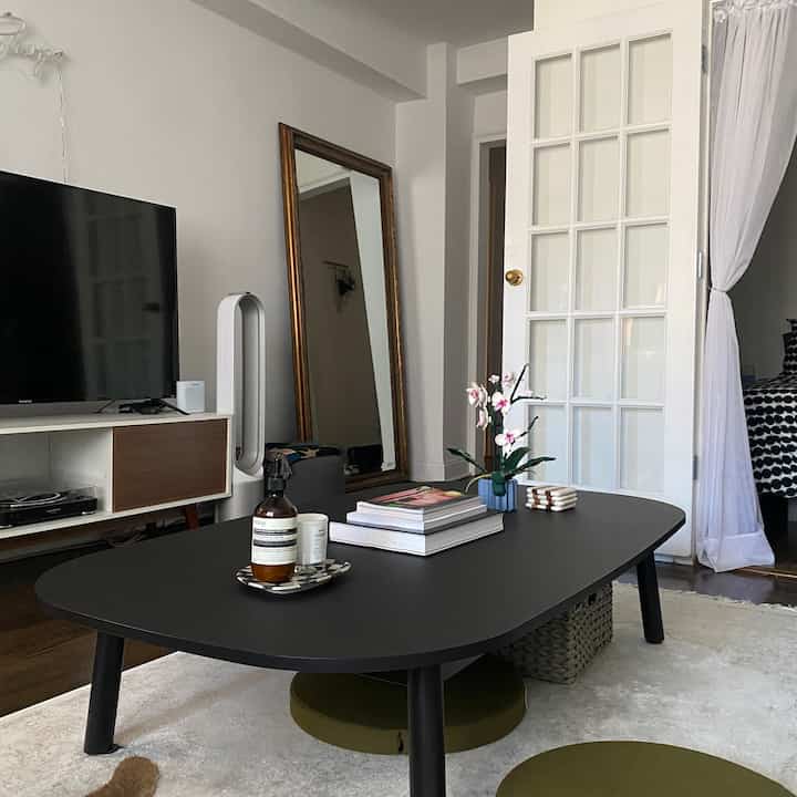 White and black toned living room featuring a black coffee table, large mirror, and TV stand, creating a modern clean atmosphere
