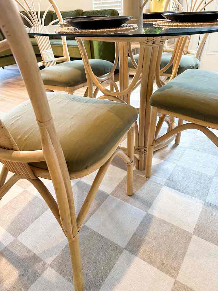 Natural wood tones and green cushions define a dining room featuring bamboo dining table and chairs in a cozy bohemian style space