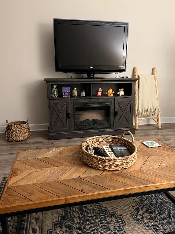Natural wood-toned living room featuring a wooden coffee table, dark brown TV stand, and a decorative wooden ladder with throw blanket creating a cozy atmosphere