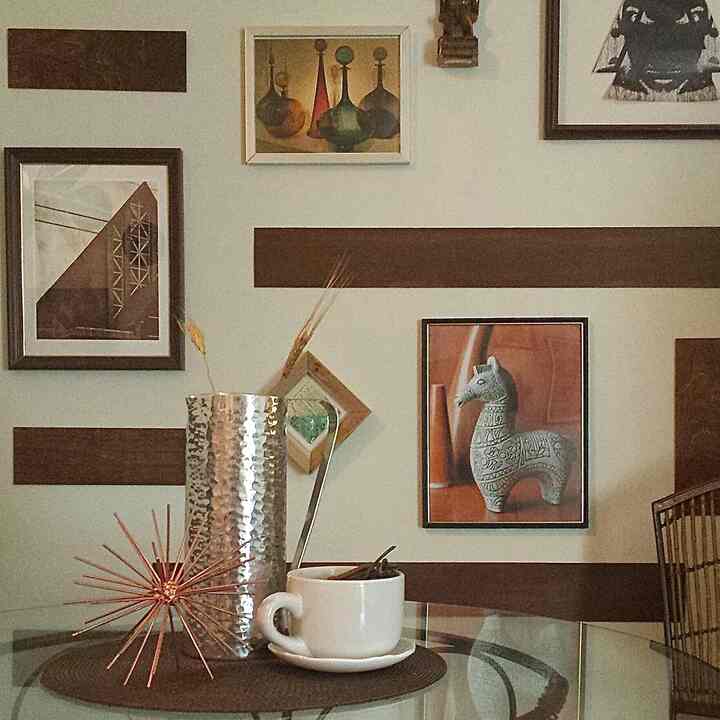 #diy #creative #walldecor #gallerywall **DIY** See those brown stripes on the wall in the first picture? They are not painted on the wall. They are balsa ￼wood slats that come in their natural blond wood color. But I applied a walnut wood stain to them for color. After they dried, I applied them to the wall with a removable adhesive that removes from the wall cleanly. They are very lightweight. The reason for the project was to add stripes to the wall without actually painting the wall of my rental. You can see pictures in this post of the various ways I used those slats in my former apartments and in my current one. The slats that i am currently using in my current place are remainders from the previous uses at the other places. One of the pics shows the objects needed to do what i did. I posted two different adhesives just to show you more than one option. Either one will do. There was one time where i spray painted some of them blue. Then there was a time that i made a wall decoration to put above my bathroom’s mirror. 
