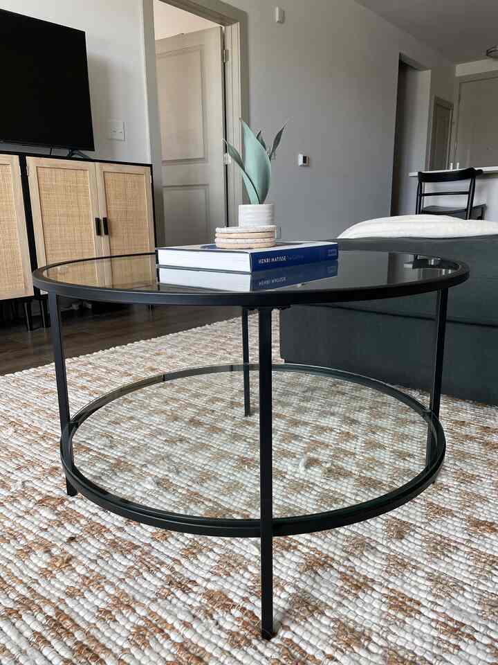 Natural brown and white toned living room featuring round glass coffee table and rattan sideboard in a harmonious bohemian modern style