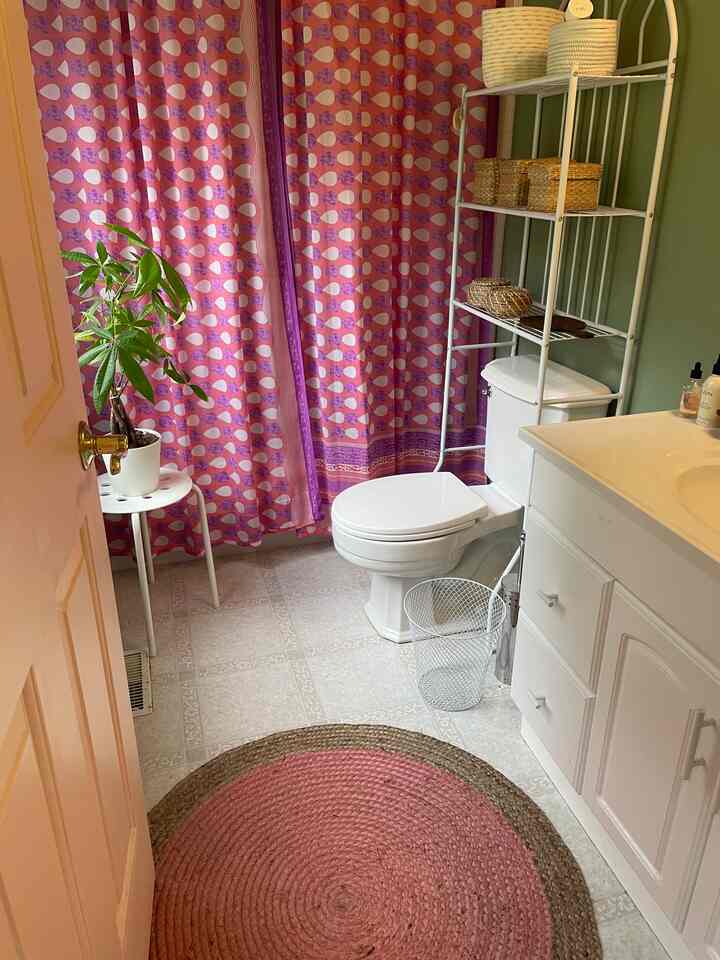 Natural style bathroom with hot pink patterned shower curtain and white bathroom fixtures