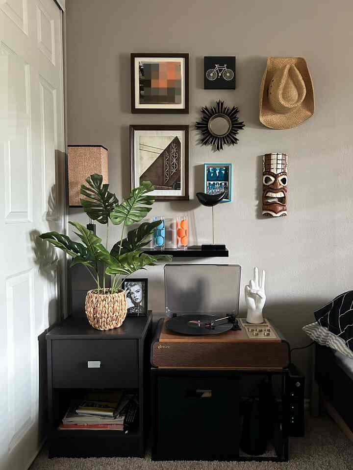 Modern bedroom with gray walls and dark brown nightstand, featuring a gallery wall and a turntable with natural tones