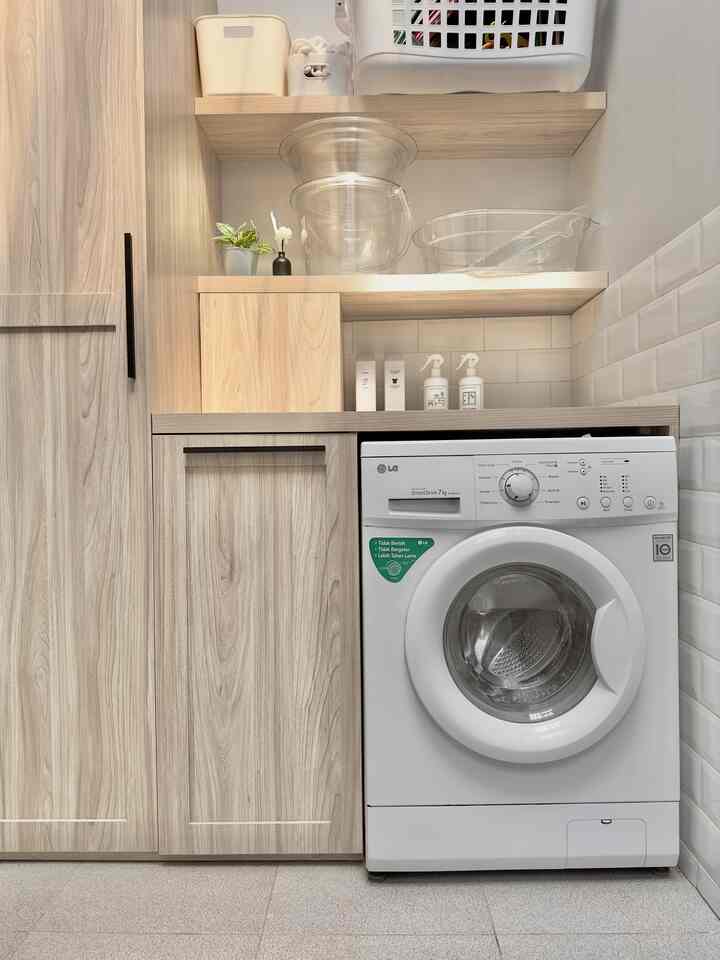 Wood tone and white laundry room featuring custom cabinets and washing machine in a compact, practical space