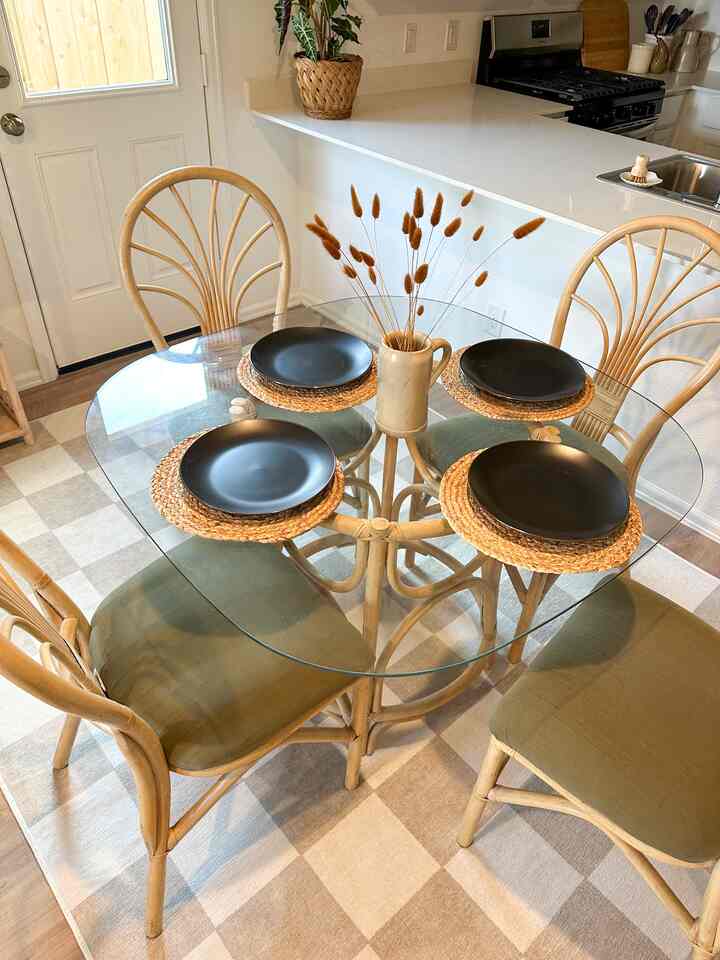 Natural color-toned bohemian dining room for four featuring glass table and bamboo chairs with cozy atmosphere