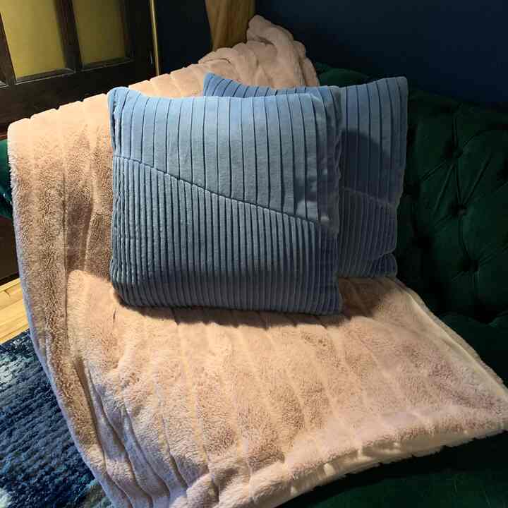 Cozy living room featuring a green sofa with pink blanket and blue cushions