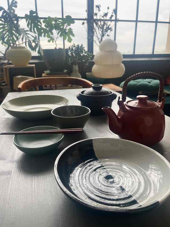 Brown wood tone dining table featuring Japanese tableware and teapot in a natural dining room setting