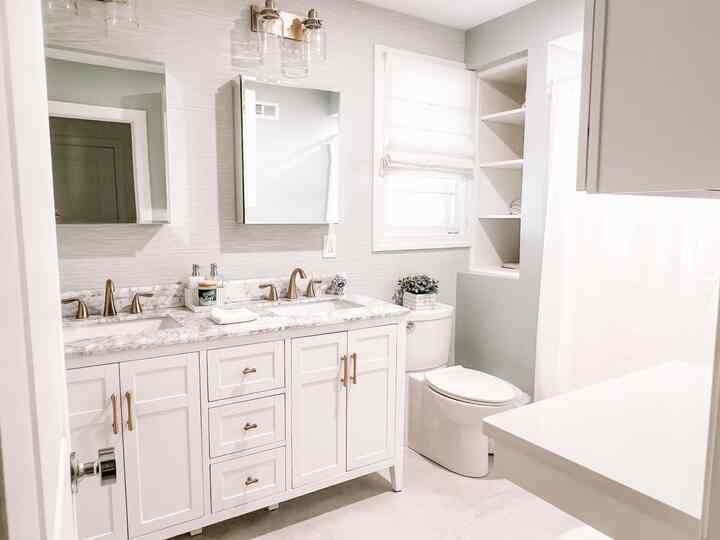 White-toned bathroom featuring a double sink vanity and organized shelving in a clean, modern space