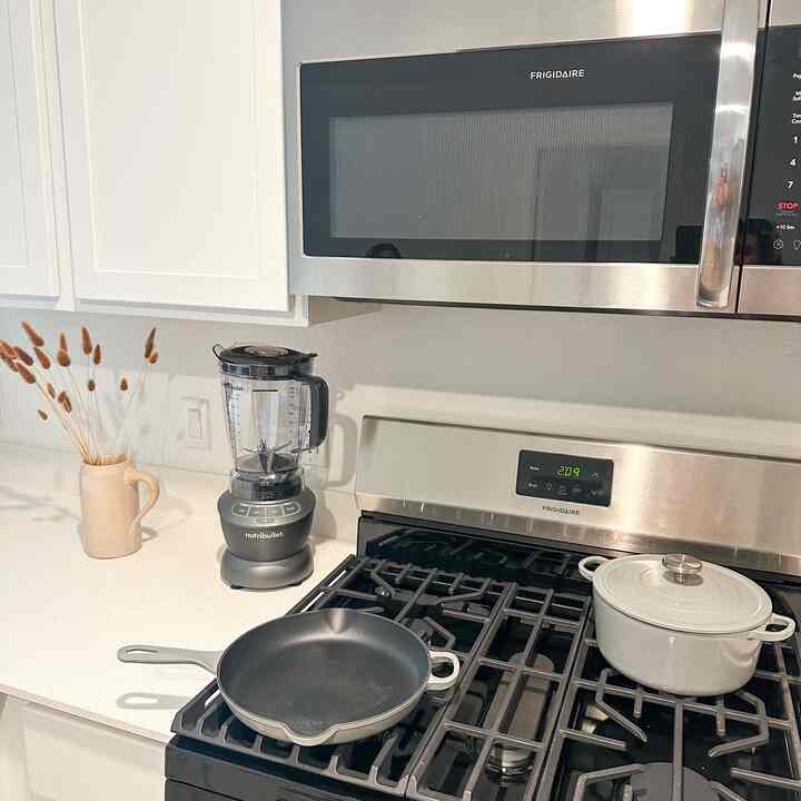 Modern kitchen in white and gray tones featuring cookware and appliances with a vintage touch and organized layout