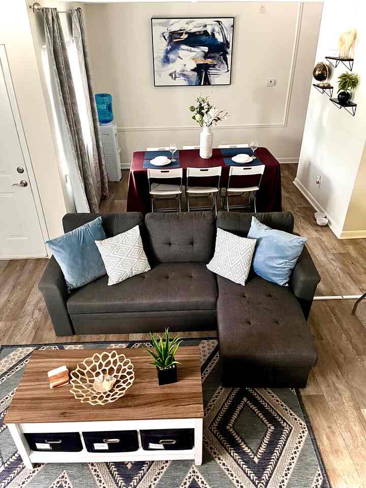 Natural-toned living and dining room featuring dark gray sectional sofa and wooden coffee table in a cozy setting