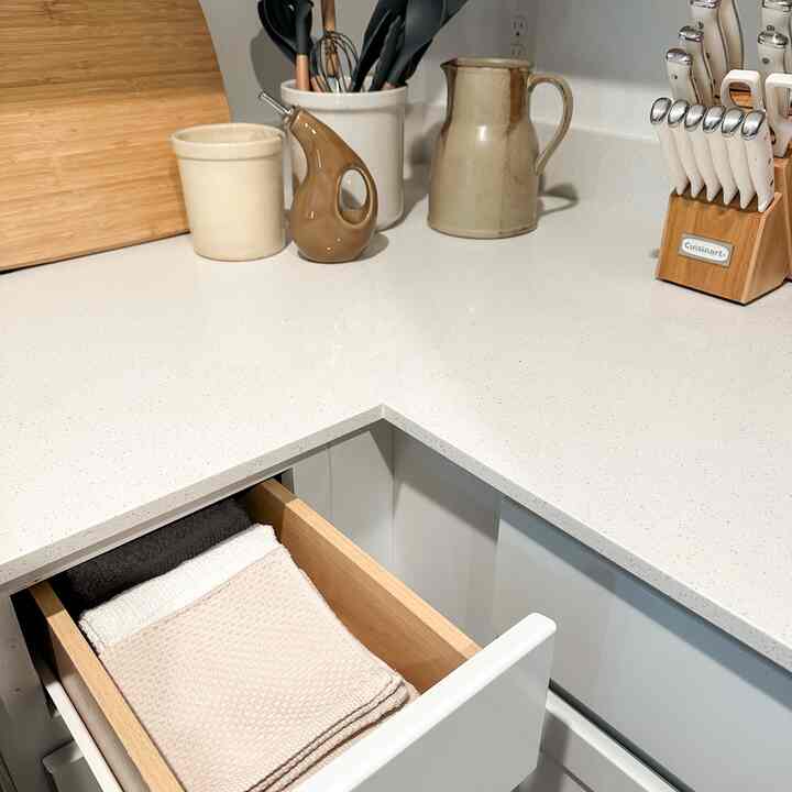 White and natural-toned kitchen corner featuring organized towels and kitchen utensils creating a cozy atmosphere