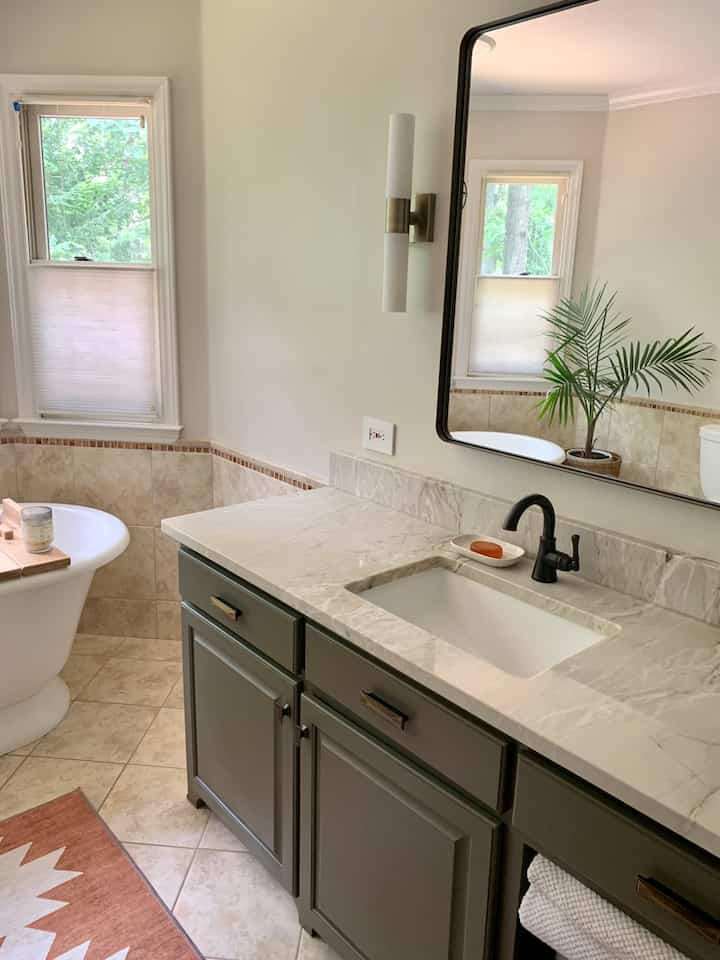 Our  #masterbathroom needed a glow-up from the pinky-orange countertops and sage green walls. I wanted a #calm, serene space. We replaced the granite with sea pearl  #quartzite, painted the walls a creamy white and painted the vanity a deep, green-brown to meld the countertop with the #travertine tile.  