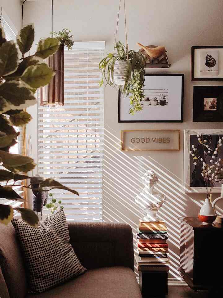 Brown and white toned living room featuring a vintage cabinet, classic Roman bust, assorted picture frames, and plants creating a warm atmosphere