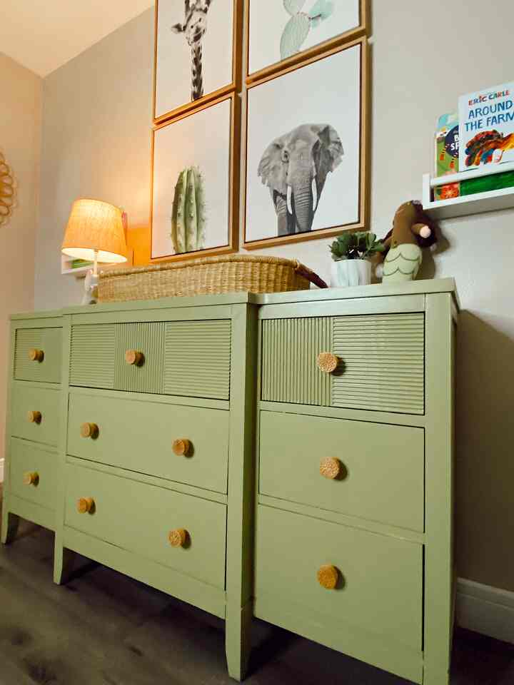 Natural green-toned dresser in a gender-neutral nursery room for baby and kids with cozy wall art and soft lighting