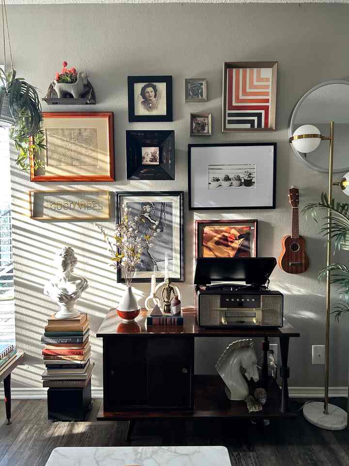 Warm wood-tone living room corner featuring vintage cabinet, floor lamp, and gallery wall art with cozy atmosphere