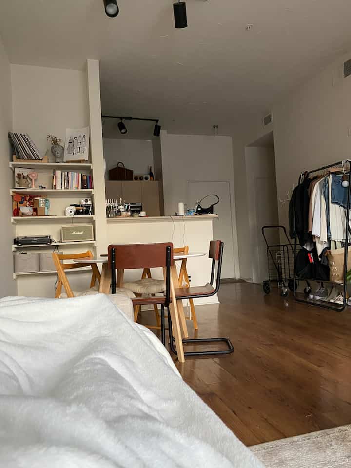 Natural color and wood tone living room featuring white microplush blanket on sofa, round dining table with chairs creating cozy atmosphere