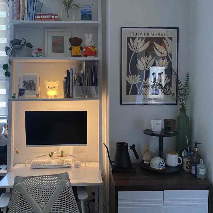White-toned compact home office featuring an office chair and ladder-style white desk with organized shelving