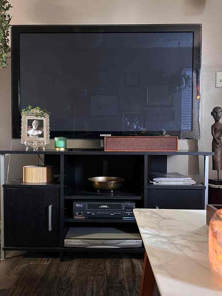 #furniture #decor #bluetoothspeaker #tv #maximalist #maximalism #apartment #rental **Tv and Random Decor** I’ve never mounted a television on a wall and I don’t plan to. I don’t feel the need to and it’s just work that I don’t want to do. Plus, it’s gonna make big holes in my rental’s wall. Nor do I ever consider a television an eyesore in a room. They’ve been obvious in peoples’ living rooms or recreation rooms for many many years and are part of our every day lives. Now onto another subject. It’s very possible that I will be moving into a new apartment soon. I am halfway excited about that considering that I have found a couple that are bigger than mine and are a lower rent rate. No matter if I stay in this small apartment or move to a bigger one, I think I will experiment with a little bit of minimalism. ￼It’s￼ easy for me to be a maximalist because I love stuff and I love decorating and while I’ve received many comments on other social media platforms about my apartment and how lovely it is, they usually tend to say that while I have a lot of stuff it doesn’t look cramped or too busy to their eyes. I agree for the most part, but there are moments lately that I think there’s just a little bit too much for this 884 sq. ft. unit. 