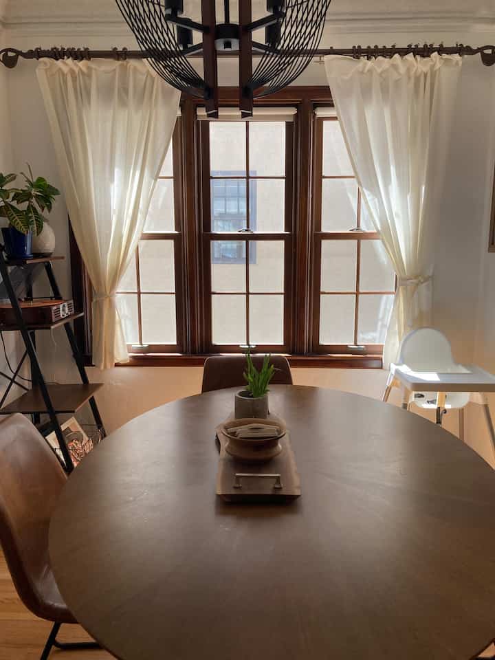Bright natural tone dining room featuring a round wooden table, leather dining chairs, and a child high chair