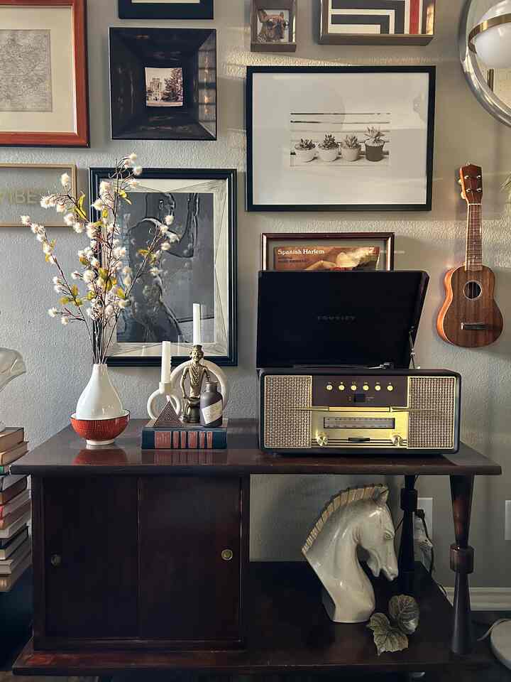 Light brown wood tone living room corner featuring plants, vintage cabinet, framed art, and retro music equipment