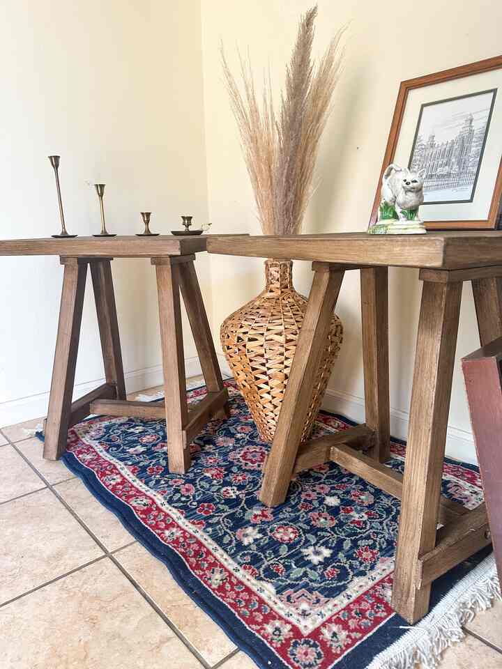 Natural wood tone vintage style space featuring two tables at center with large rattan vase and pampas grass